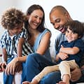 A warm and joyful family of four sitting on a couch.